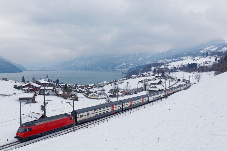 A train passes Lake Thun in a snow-covered Spiez