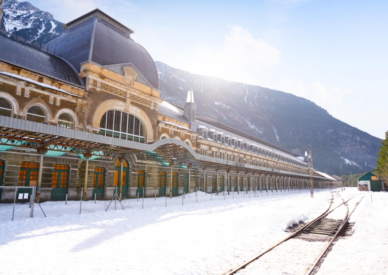 The facade of Canfranc Station in winter, with mountains in the background