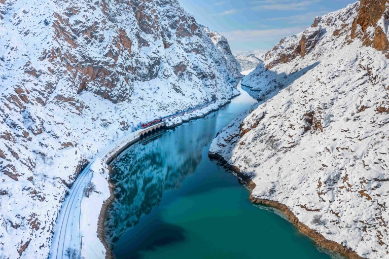 A Dogu Express train cuts through a canyon in winter